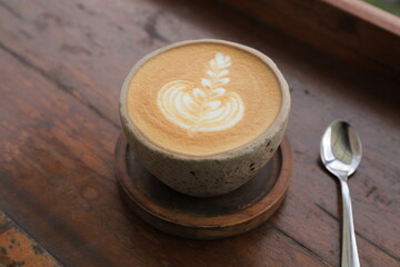 A cup of cappuccino on a brown wooden table. Great for backgrounds. text or Copy space