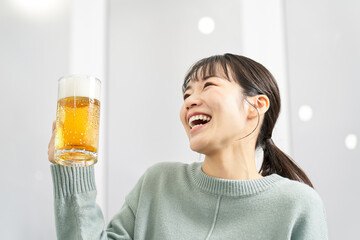 自宅でジョッキでビールを飲む女性