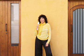 A woman in a yellow sweater holding a white ice cream cone
