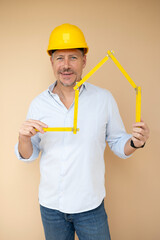man, architect, technician, builder, polisher with yellow safety helmet and yellow folding rule against a brown background