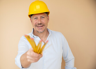 man, architect, technician, builder, polisher with yellow safety helmet and yellow folding rule against a brown background