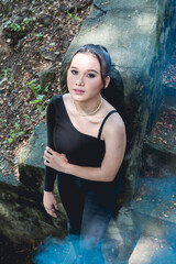 Young woman in goth-inspired attire posing in a mystical forest setting