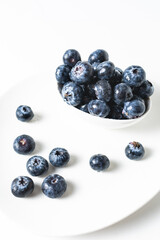 Fresh blueberries in a white bowl on a white background, with room for text