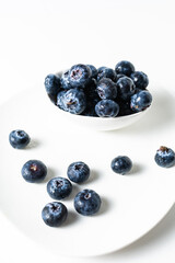 Fresh blueberries in a white bowl on a white background, with room for text