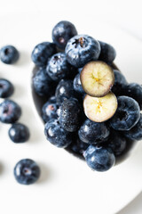 Fresh blueberries in a white bowl on a white background, with room for text