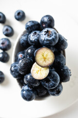 Fresh blueberries in a white bowl on a white background, with room for text
