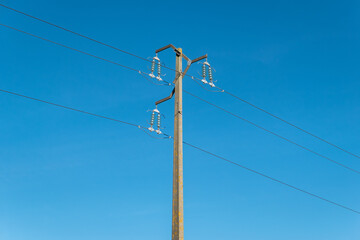 Obraz premium Contrastes energéticos: Poste elétrico e linhas de alta tensão em harmonia com o céu azul
