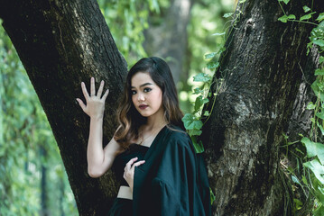 Young woman in gothic attire posing in a lush forest setting