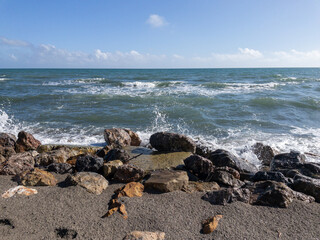 Fototapeta na wymiar Veduta marina, scogli e onde che si frangono sulla spiaggia in primavera