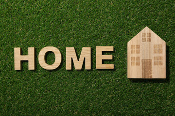 The word home in wooden letters on green grass