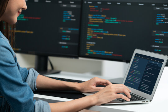 Smiling young Asian in IT developer creating with typing online information on laptop with coding program data of application, wearing jeans shirt. surrounded by safety analysis two screen. Stratagem.