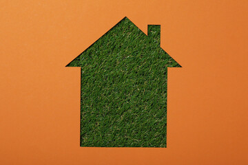 The house is cut out of paper on the grass