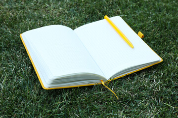 An open notebook with a pen on the grass