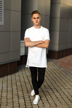 Cool fashion handsome man with hairstyle in a white T-shirt with black jeans and white sneakers