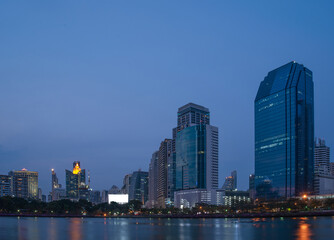 A serene twilight view of a city's illuminated skyline with reflections shimmering on the water's surface..