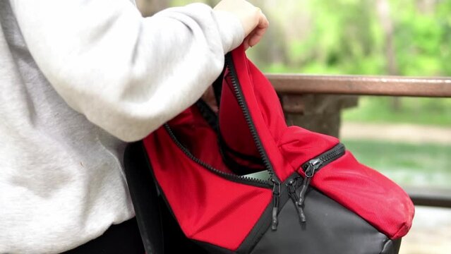 Woman takes a tupperware of food out of her backpack at a picnic table in the rest area of a nature trail
