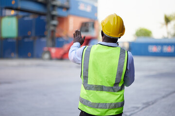 back view African worker or engineer using walkie talkie and showing gesture to crane car in...