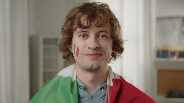 Man Italian football fan cheering for favorite Italy team, with painted flag on cheeks. World Sport games USA, Canada, Mexico. Football, sports and soccer fans. Slow Motion