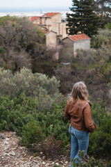 Picturesque view of the nature of Liguria - A blonde woman admires a magnificent view from the mountain of an old mansion and a picturesque valley along the coast