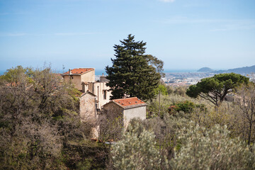 Fototapeta na wymiar Picturesque view of the nature of Liguria - view from the hill of an old house with a tiled roof against the backdrop of the sea
