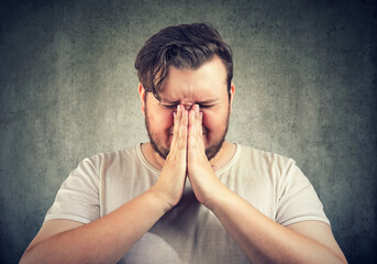 Closeup portrait of a sad, desperate young man praying  - 788070743