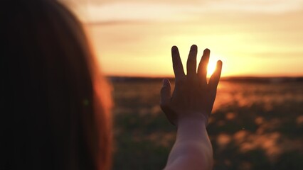 Woman stretched out hand sunset silhouette. Girl traveler in field dreams prays contemplates environment beauty sunlight shines through fingers. Connection with spiritual religious hope faith belief.