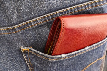 A brown wallet in the back pocket of jeans. Close-up.