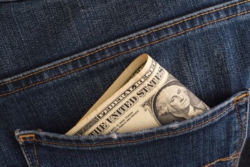 A close-up shot of a one dollar banknote in the back pocket of blue jeans.