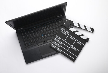 Laptop with a clapperboard on a blue background. Top view