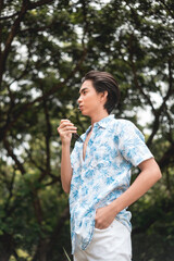 Young man in a tropical print shirt contemplating in a lush forest setting