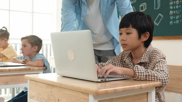 Caucasian teacher helping asian student coding engineering prompt while diverse student using software generated AI. Smart happy attractive children sitting and programing system. Education. Pedagogy.