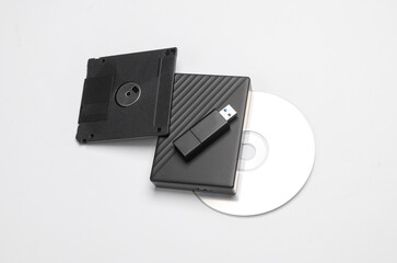 CD disk with floppy disk, USB flash drive and external hard drive on a white background. Digital...