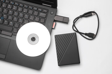 Storage media. Laptop with CD disk, sd card, USB flash drive and external hard drive on white background.