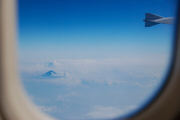 Naklejka na ściany i meble 飛行機の窓から見える富士山と雲の風景写真