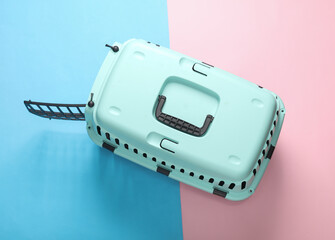 Plastic pet carrier on blue pink pastel background. Top view