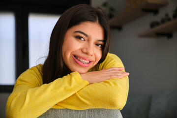 Latin female teenager with braces smiling and looking at camera.