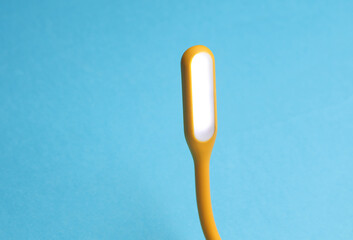 Flexible yellow USB lamp on blue background.