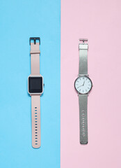 Modern smart and analog watches on a blue-pink background. Top view