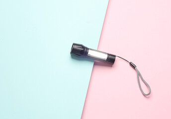 Pocket flashlight on blue pink background. Top view