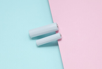 White blank aa and aaa batteries or accumulators on a blue-pink background. Mockup for design