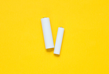 White blank aa and aaa batteries or accumulators on a yellow background. Mockup for design