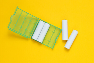 White blank aa batteries or accumulators in box on a yellow background. Mockup for design