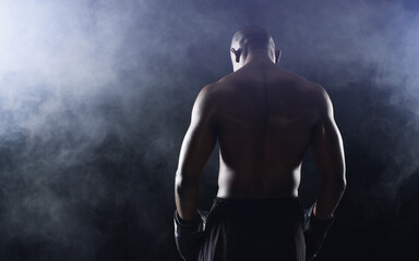 Fototapeta premium Man, boxer and back of fighter athlete on black background in studio with smoke mist, competition or muscle. Male person, gloves and rear view for sports exercise with endurance, training or serious