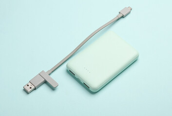 Plastic power bank with cable on blue pastel background