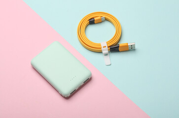 Plastic power bank with cable on blue pink pastel background
