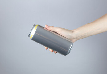 Hand holding Aluminum can for beer, soda or energy drink on gray studio background.