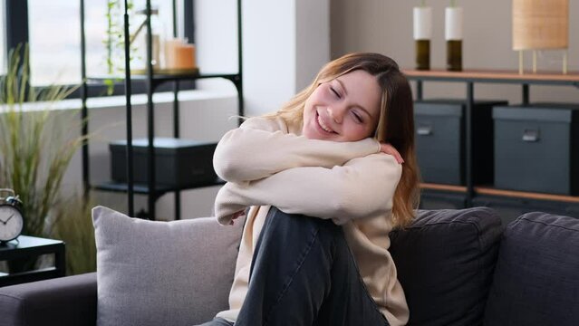Positive portrait of a Caucasian happy, glad and satisfied woman sitting on comfortable sofa at home living room. Women femininity, individuality concept.