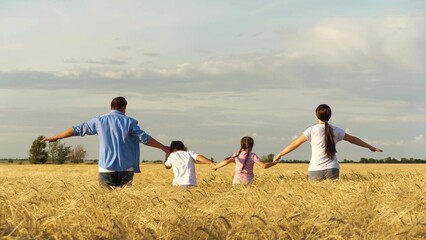Happy family running on dry wheat field with open hands together enjoy freedom back view. Mother father daughter and son playing flying imagination fantasy imagine relaxing outdoor rural plantation