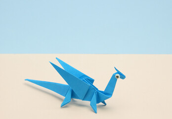 Blue Origami dragon with eyes on pastel background. Creative layout