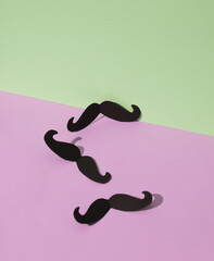 Paper-cut mustache on green-pink pastel background. Creative minimal layout. Father's day